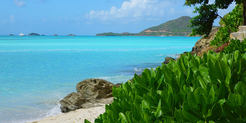 A beach with green bushes, rocks and azure waters in Antigua