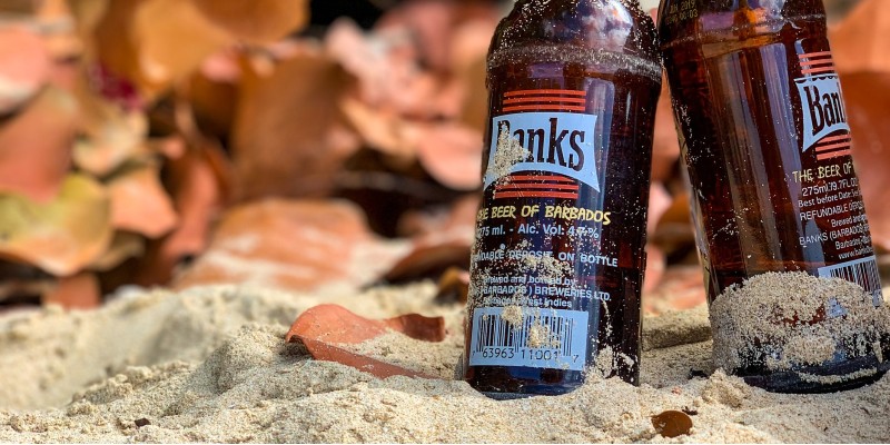 Two empty brown glass bottles standing on sand 