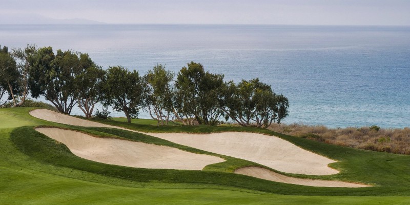 View from a golf course with sand dunes and ocean background