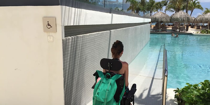 A woman in a wheelchair makes her way down the ramp to an outdoor swimming pool at a resort in Dominican Republic