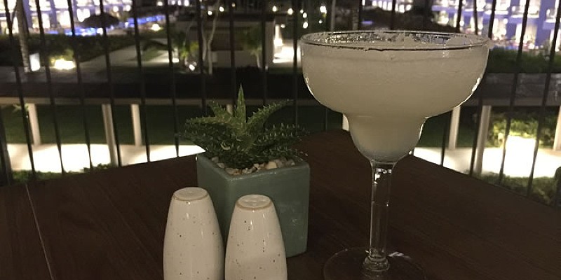 A drink and salt & pepper shakes on a table at an open-air Mexican restaurant