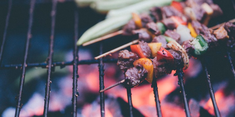 Kebabs cook on a barbeque grill over open flames