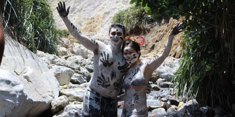 Two people pose covered in mud from Sulphur Springs St Lucia