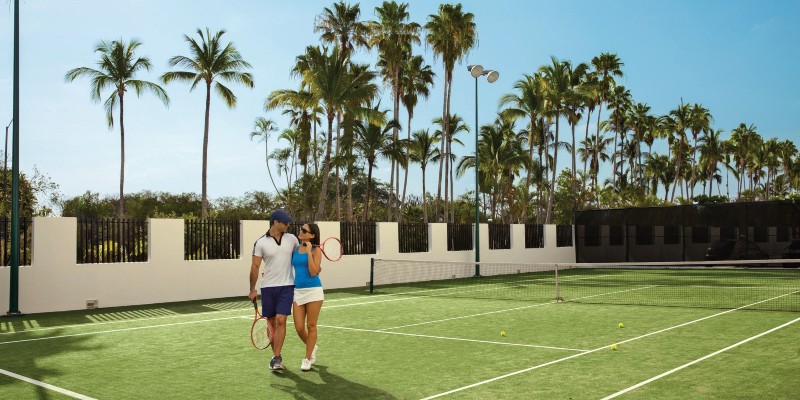 Two people hug on a tennis court in a Mexico resort