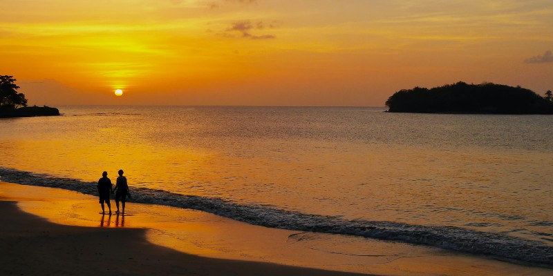 Two people walking on the beach at sunset in St Lucia