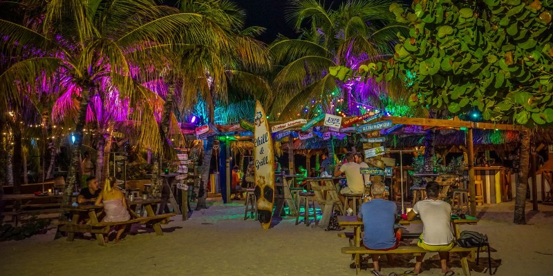People sat drinking at a Caribbean beach bar in the evening 
