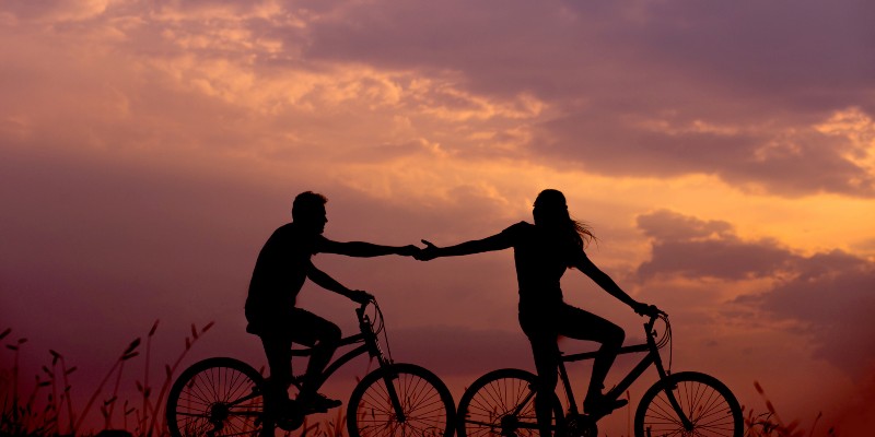 Two people riding bicycles at sunset