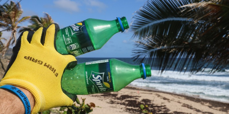 Person holding two plastic bottles collected from a tropical beach