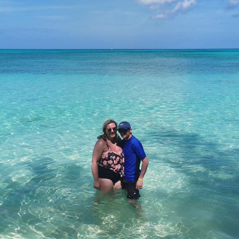 Phil and his wife pose in the ocean