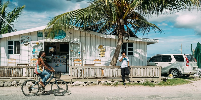Man cycling passed a man standing outside a shop in Negril, Jamaica