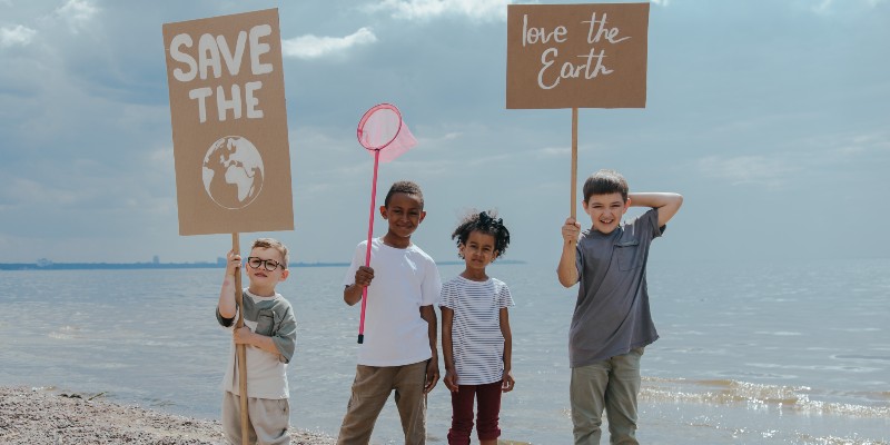 Children holding signs with environmental messages on the beach