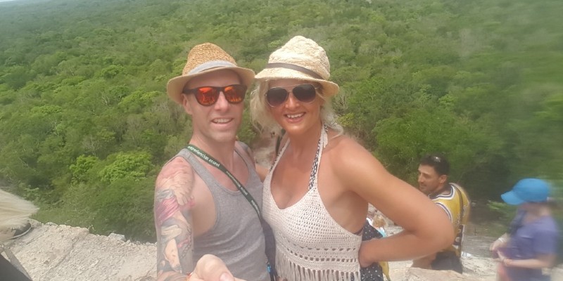 Man and a woman take a picture on top of the Mayan pyramid in Coba, Mexico