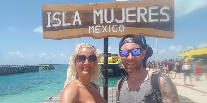 Couple posing in front of the Isla Mujeres sign