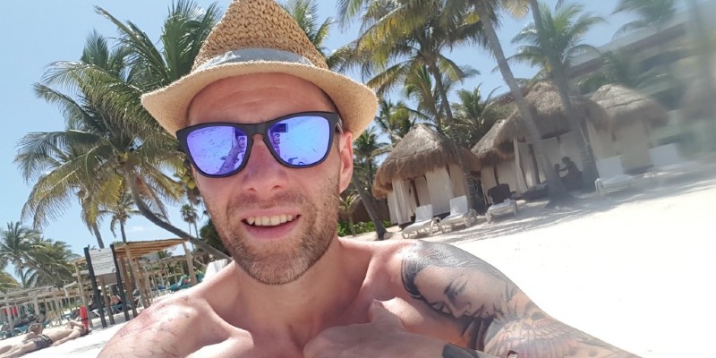 A man wearing sunglasses and a straw hat on the beach